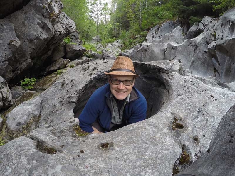 Bruce Grierson, author and founder of One Big Day, sitting in a karst hole